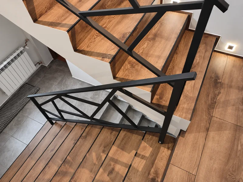 Geometryczna balustrada stalowa przy drewnianych schodach
