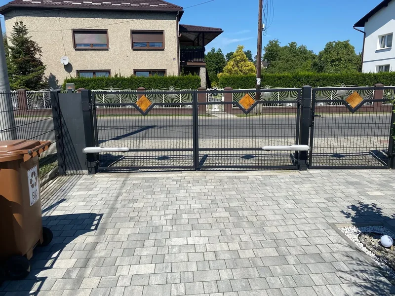 Ogrodzenie i brama z pionowym wypełnieniem oraz detalem ozdobnym